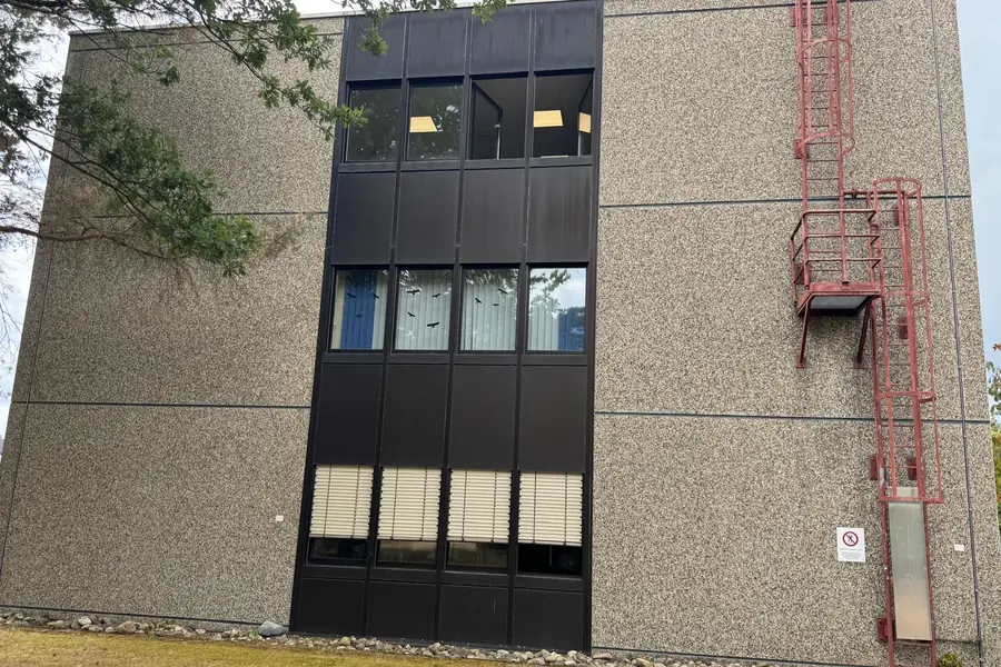 Fassade aus Waschbetonplatten mit sanierten Dehnungsfugen zwischen den Elementen, rechts eine rote Steigleiter