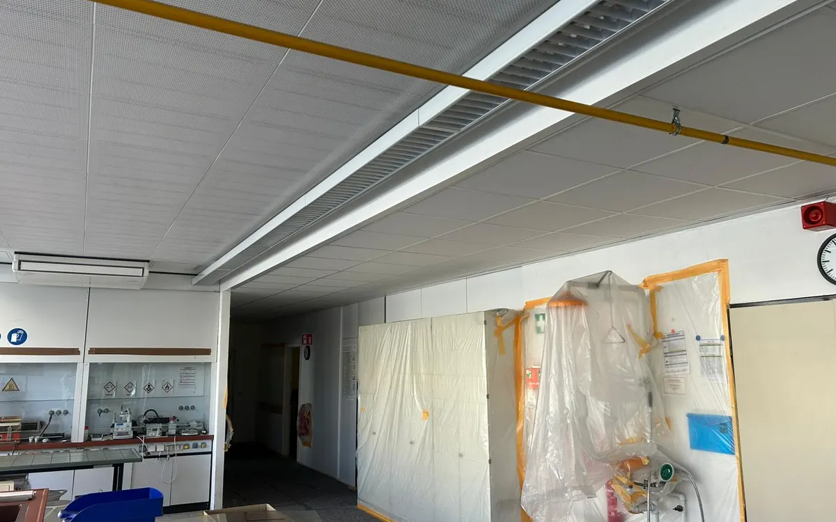 Innenraum mit geöffneter Rasterdecke und Folienabtrennung während der Umbauarbeiten